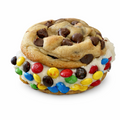A novelty sandwich cookie featuring a chocolate chip cookie on top and a bottom cookie covered in colorful M&M's candies, set against a plain white background.